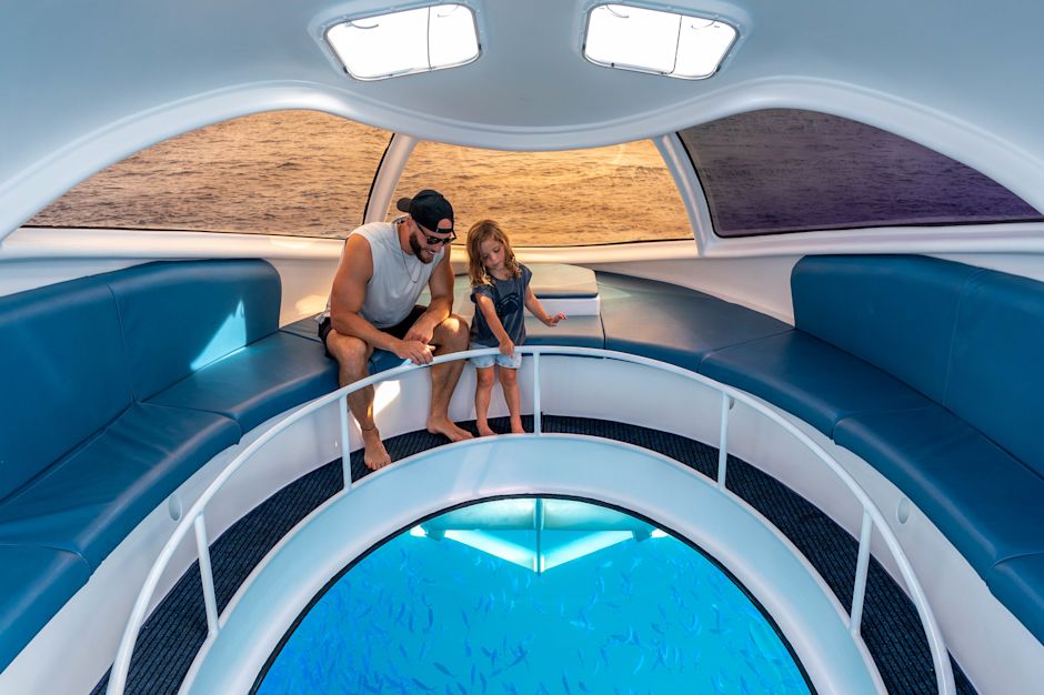 Un homme et une fille regardant un poisson dans un bateau à fond de verre