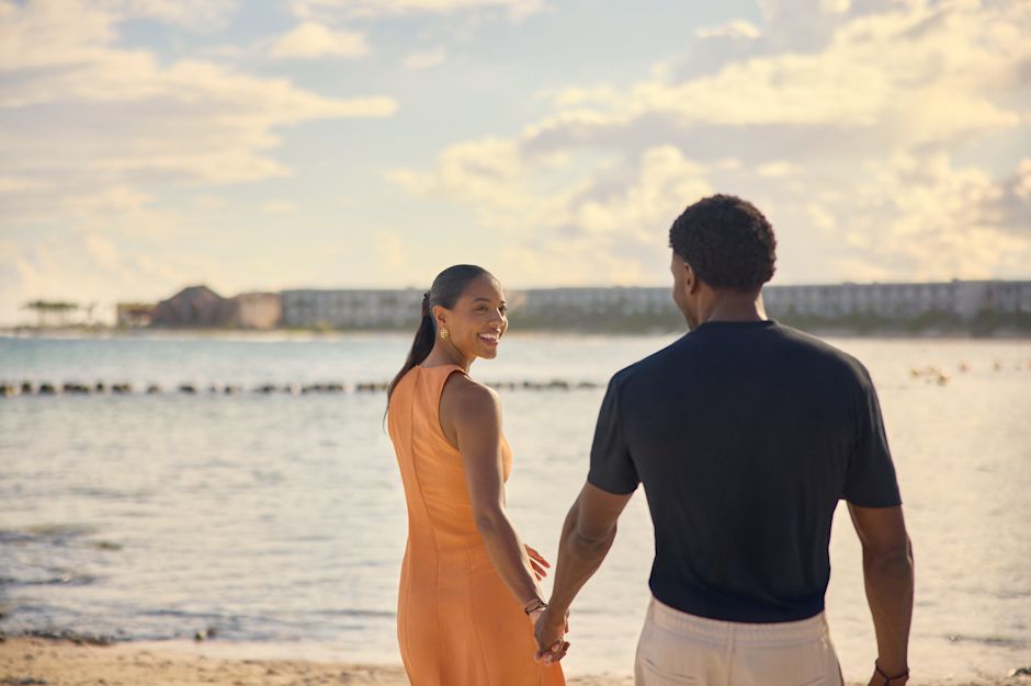 Man and woman holding hands and walking on the beach