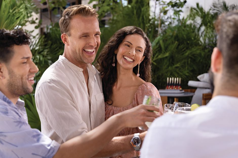 Four people clink glasses with drinks in hand