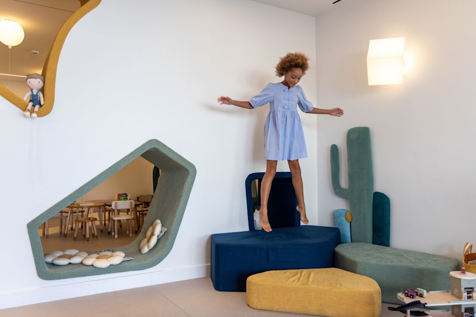 Ragazza che salta su una comoda sedia con dei giocattoli