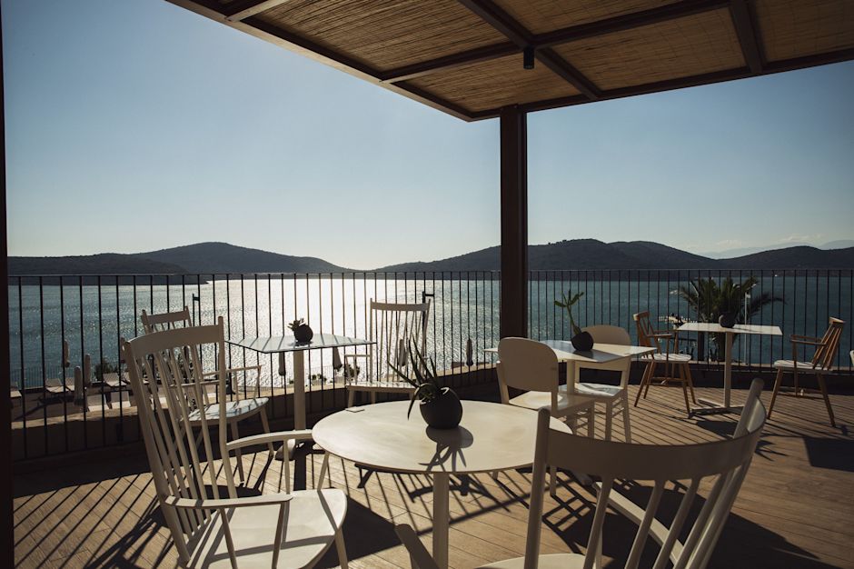 Suya bakan beyaz sandalyeler ve masalar bulunan Island restoran açık terası.