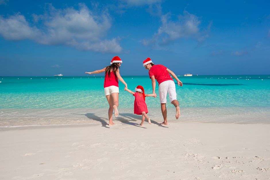 family on beach wearing santa hats