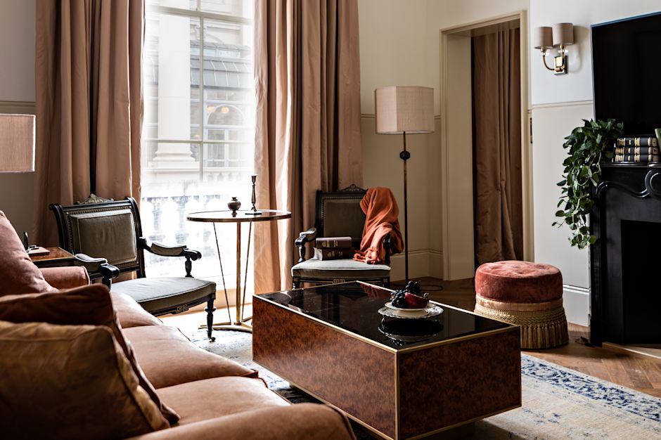 Living room with a brown velvet sofa, armchairs, floor lamp, round table, and tall curtains.