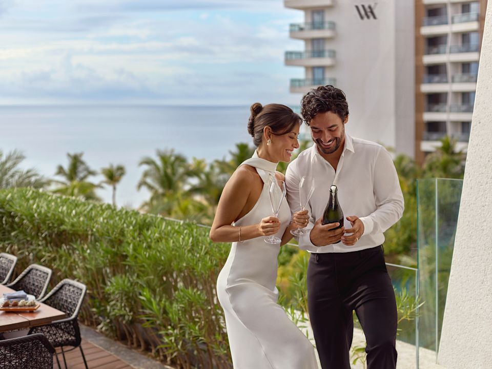 Bride and Groom about to open champagne with view of sea