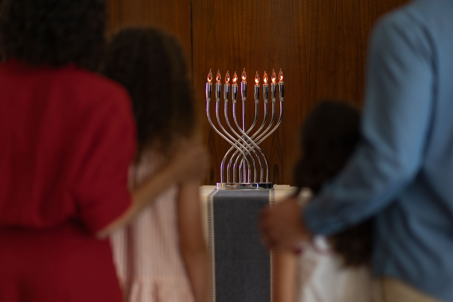 Family Standing next to a Menorah Lighting to Celebrate the Holidays