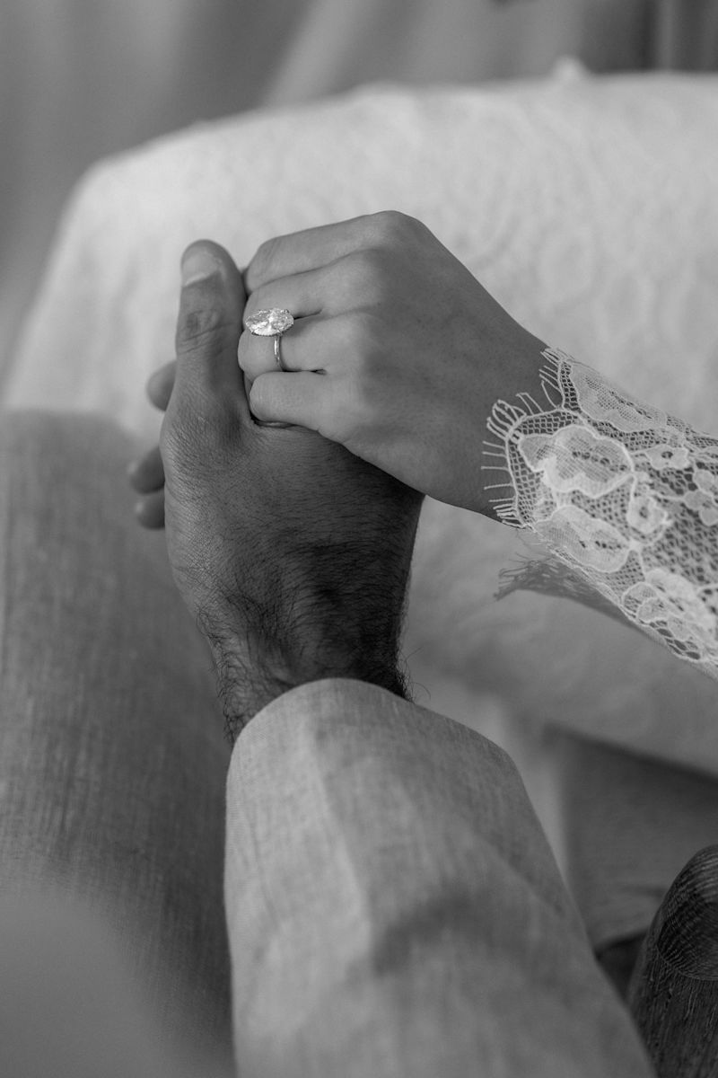 Photographie en noir et blanc d'un couple tenant la main lors de son mariage