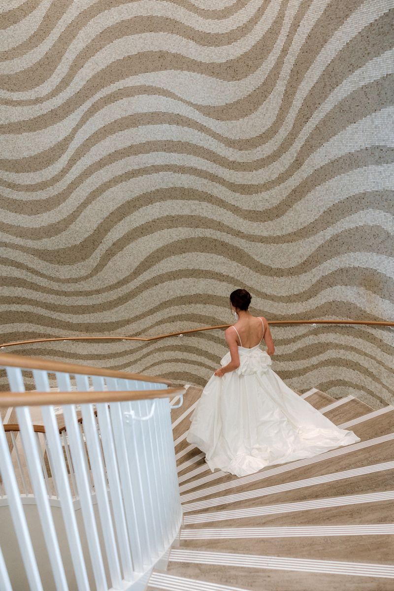 Une mariée dans sa robe de mariée descendant un grand escalier.