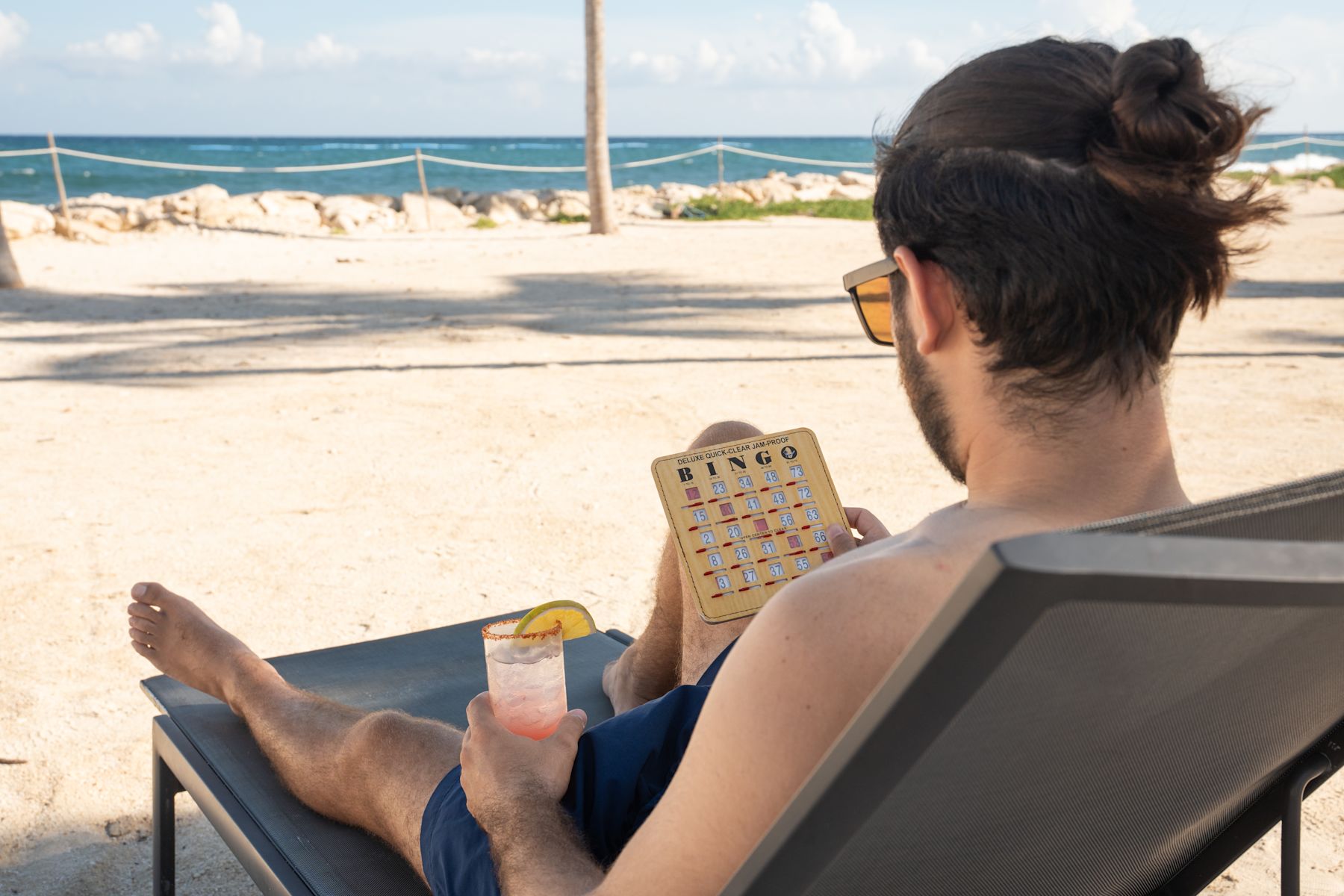 Man Lying on a Lawn Chair  at the Beach Playing Bingo