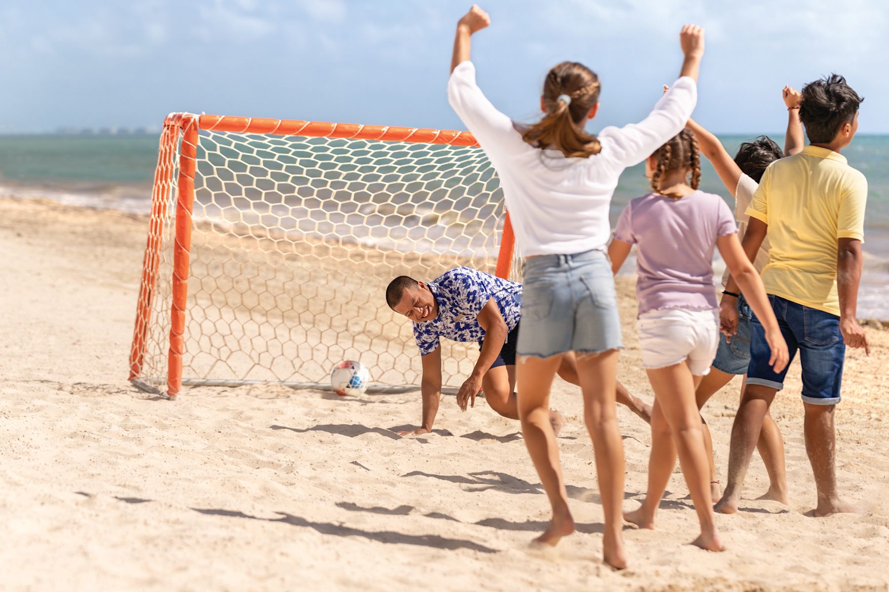 Children cheer and play soccer on the beach