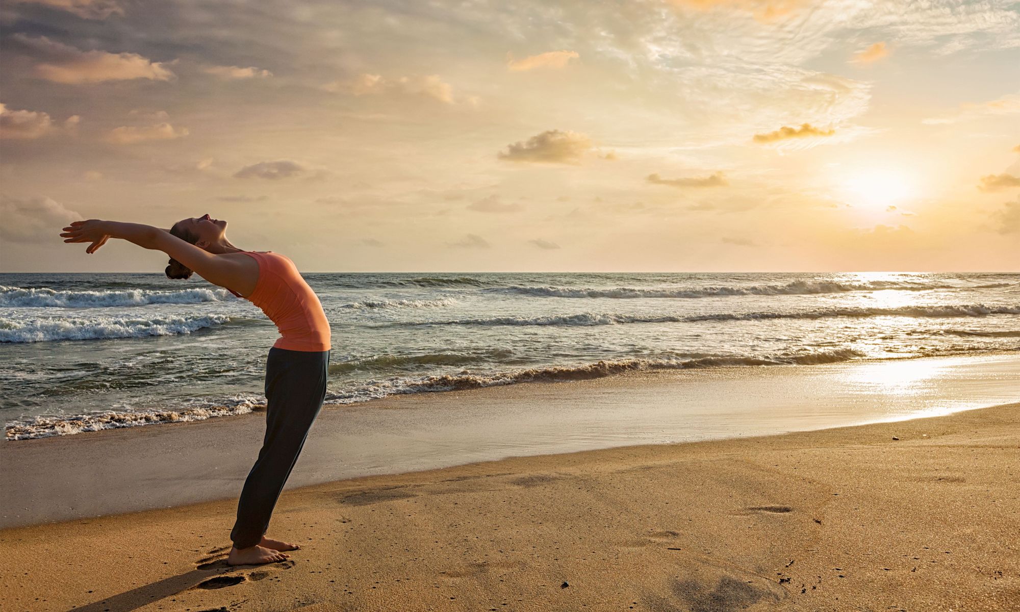 Woman Practicing Yoga on the Beach at Sunset