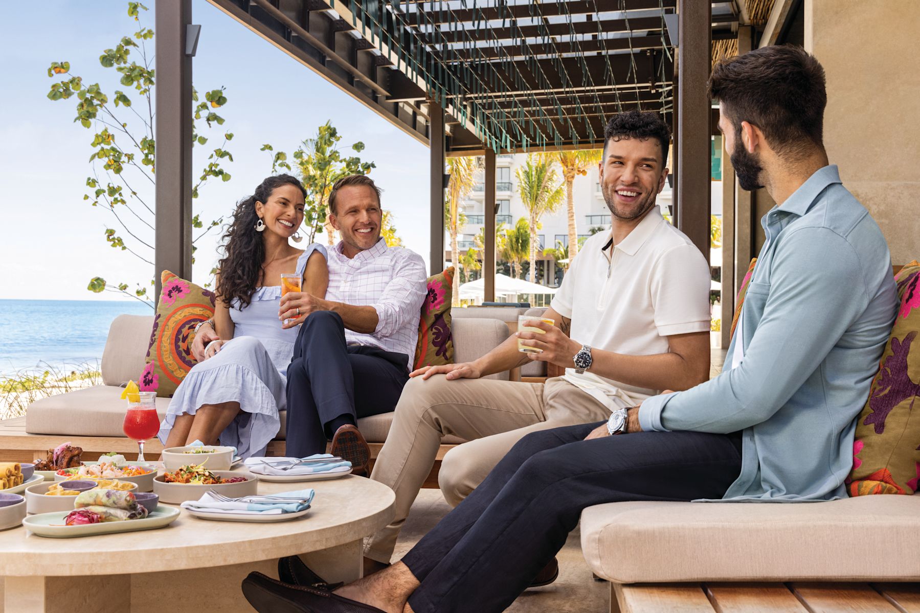 friends enjoying drinks and food at hotels outdoor restaurant by the beach