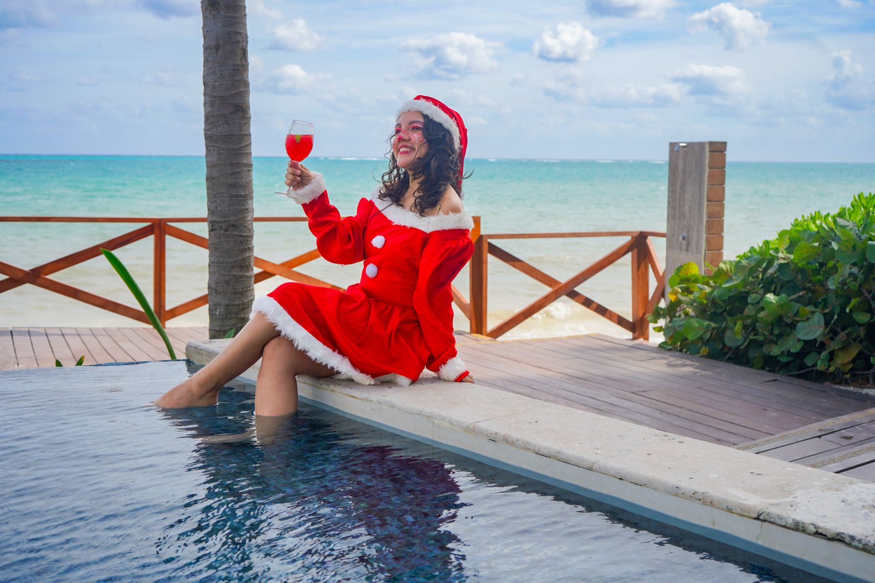 Woman in Santa outfit with legs in pool