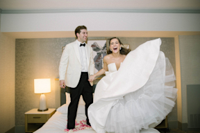 เจ้าสาวและเจ้าบ่าวกระโดดอยู่บนเตียงในห้องพักในงานแต่งงานของพวกเขา