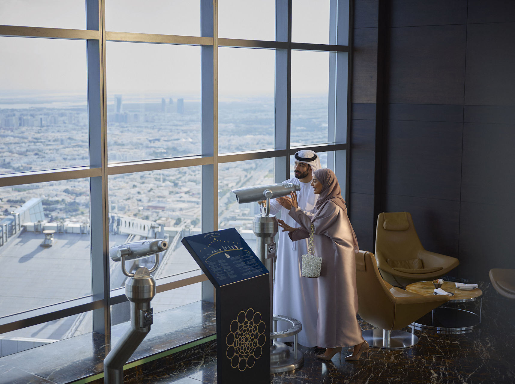 Man and woman in observation deck looking through telescope