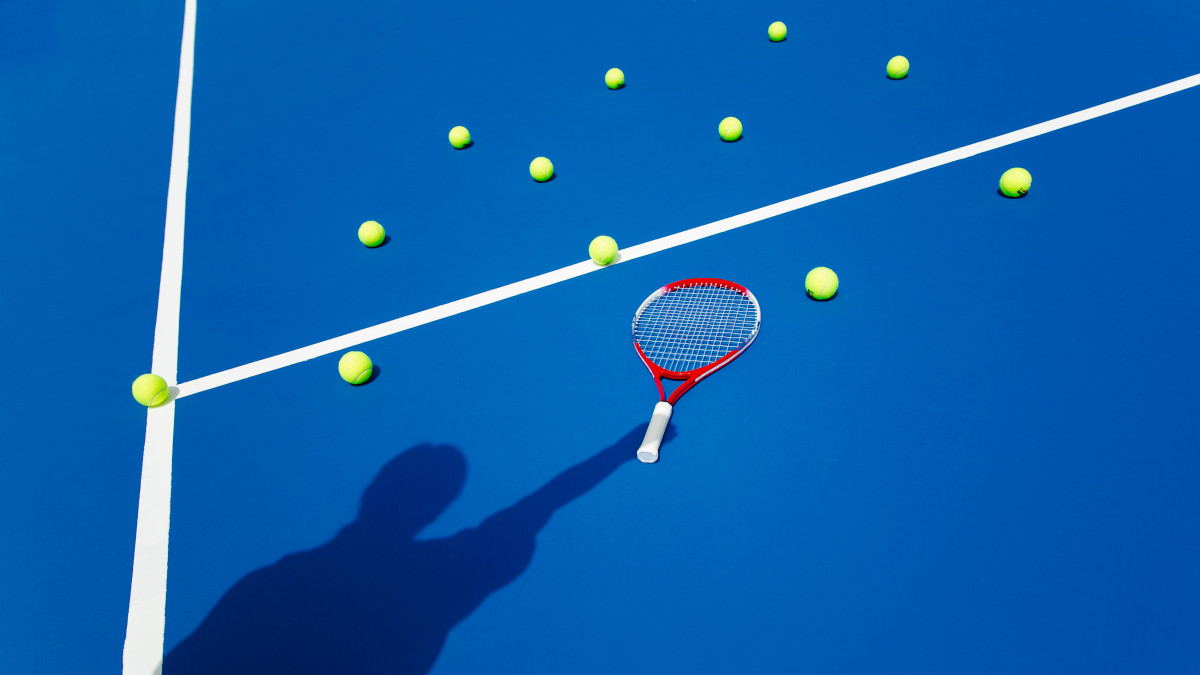 Tennis racket and balls on blue court
