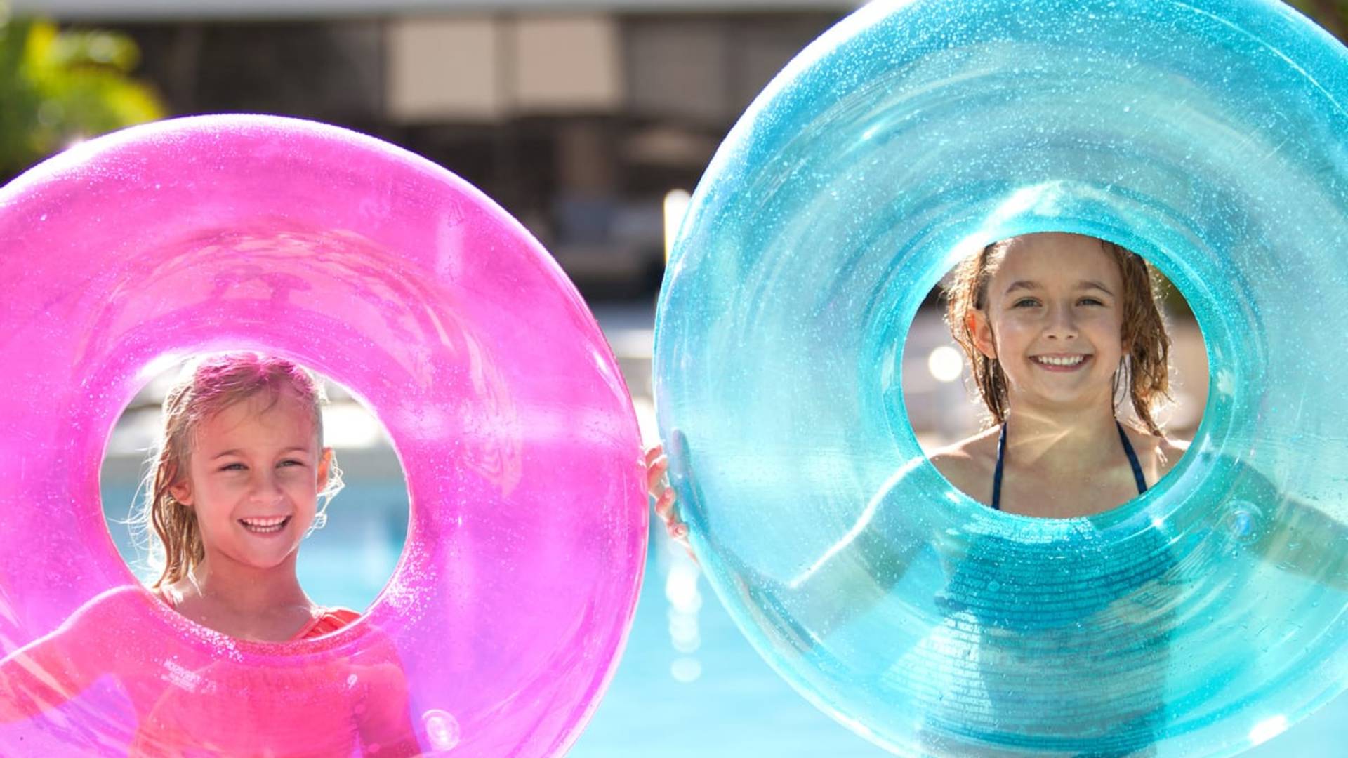 Girls holding pink and blue float tubes in a pool