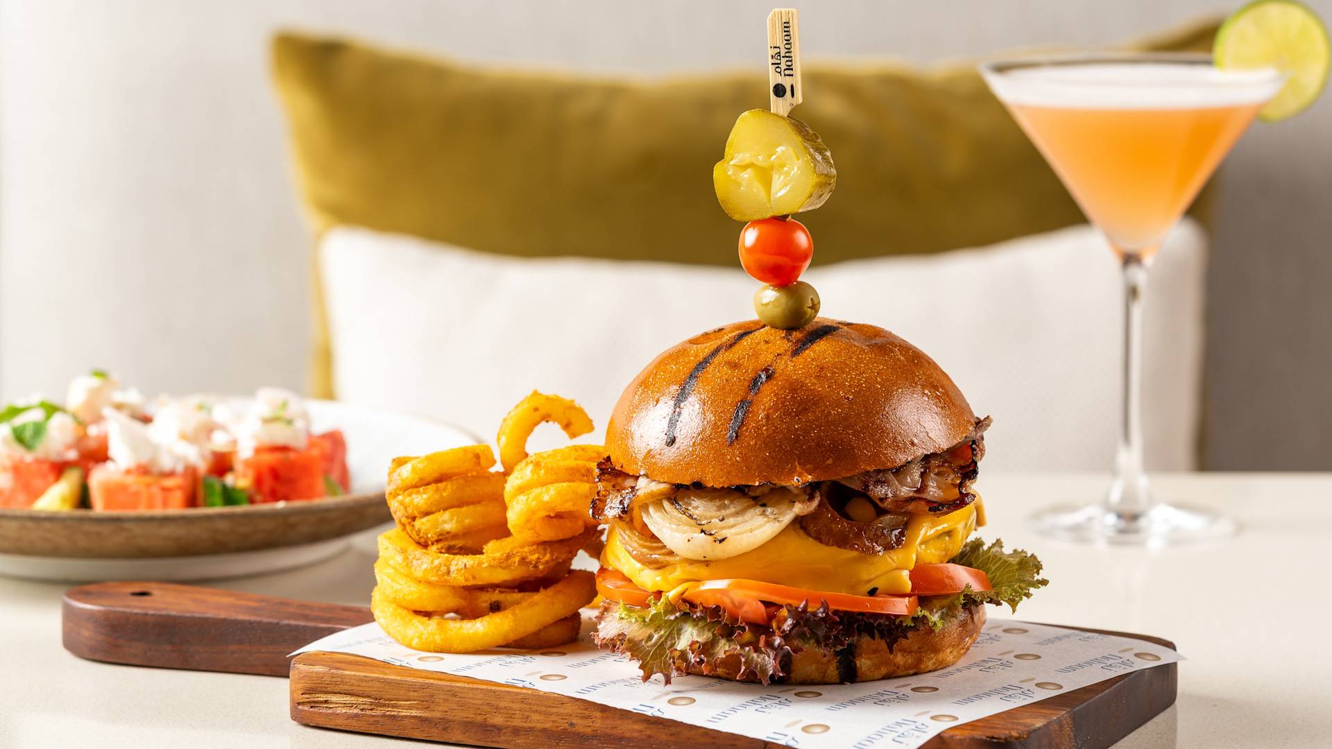 Hamburger, Curly Fries and a Cocktail on a Table at Nahaam Restaurant
