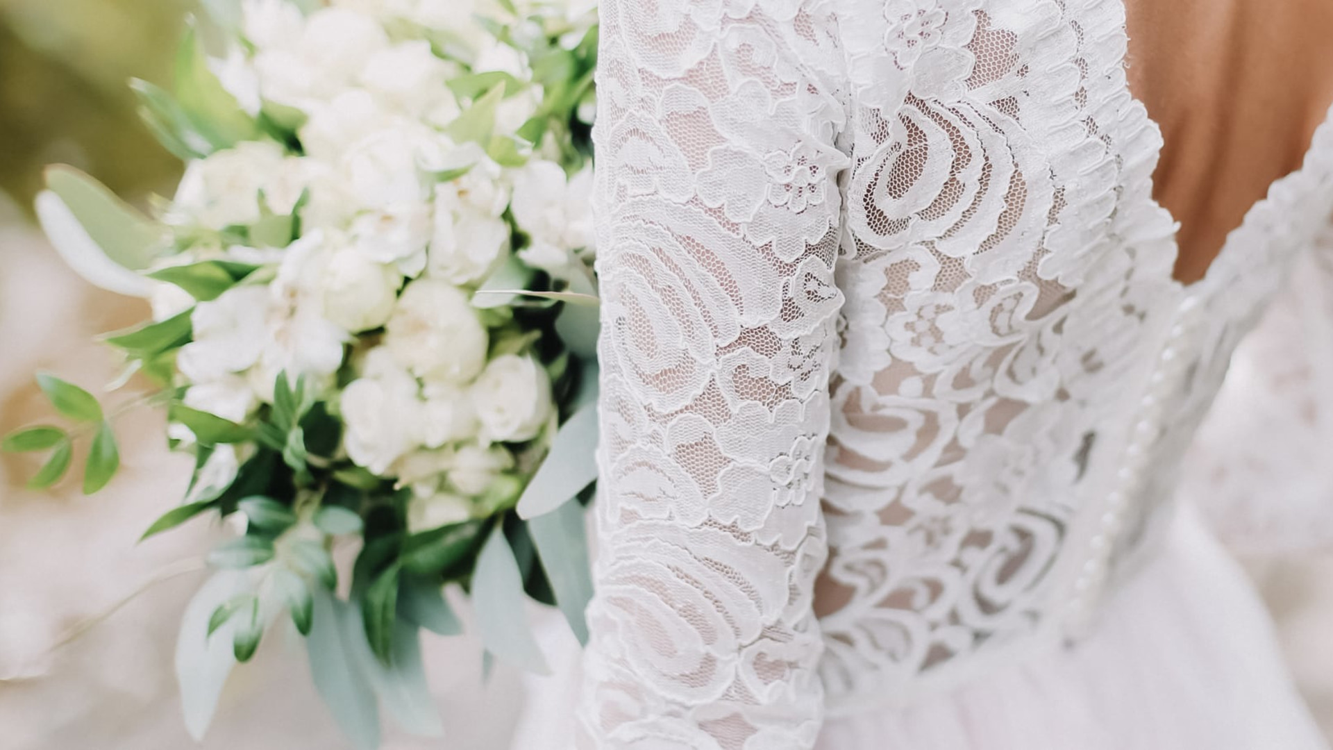 Detail of the back of a bride's wedding dress and bouquet