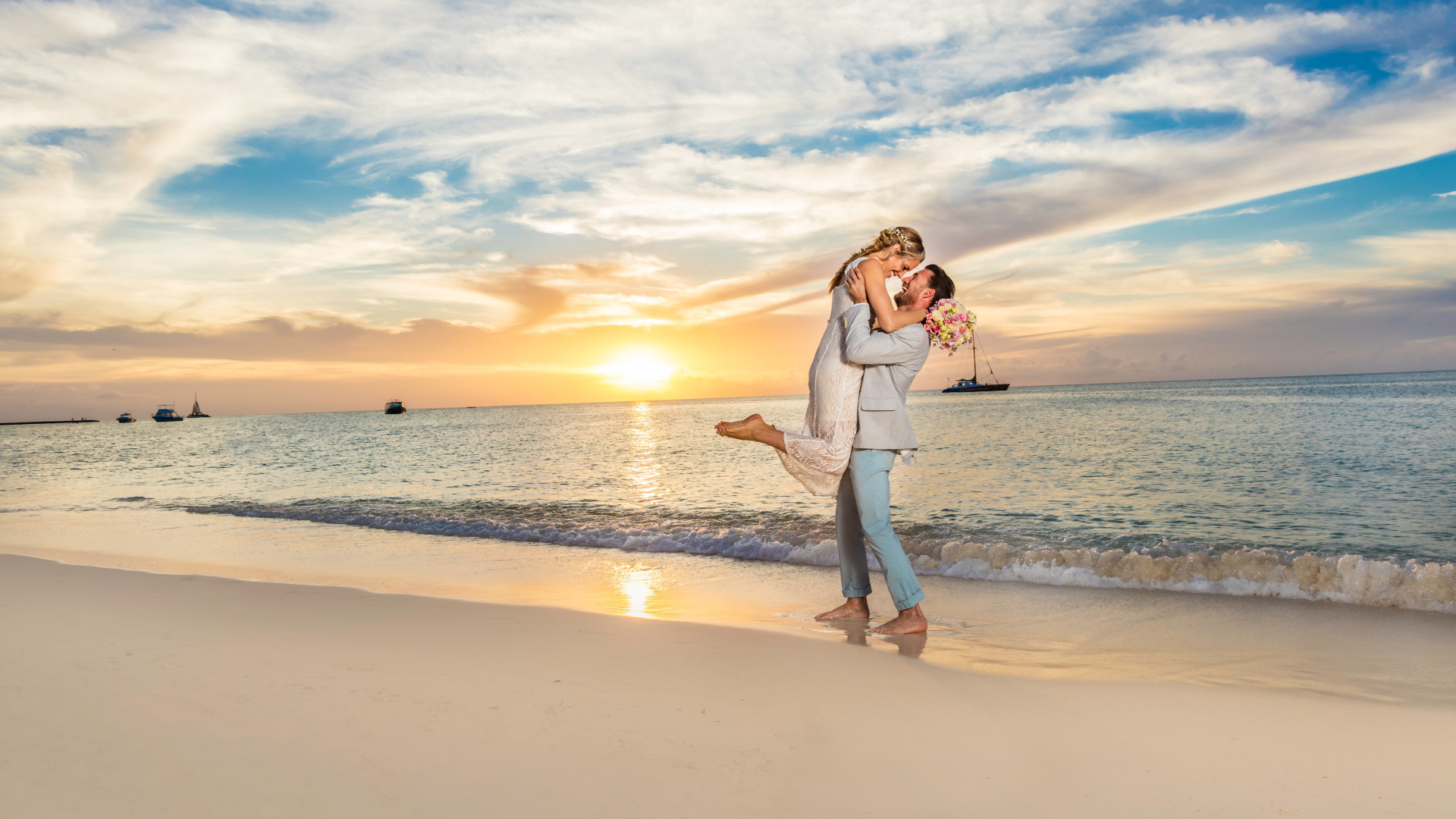 Wedding couple on beach - man lifting woman up