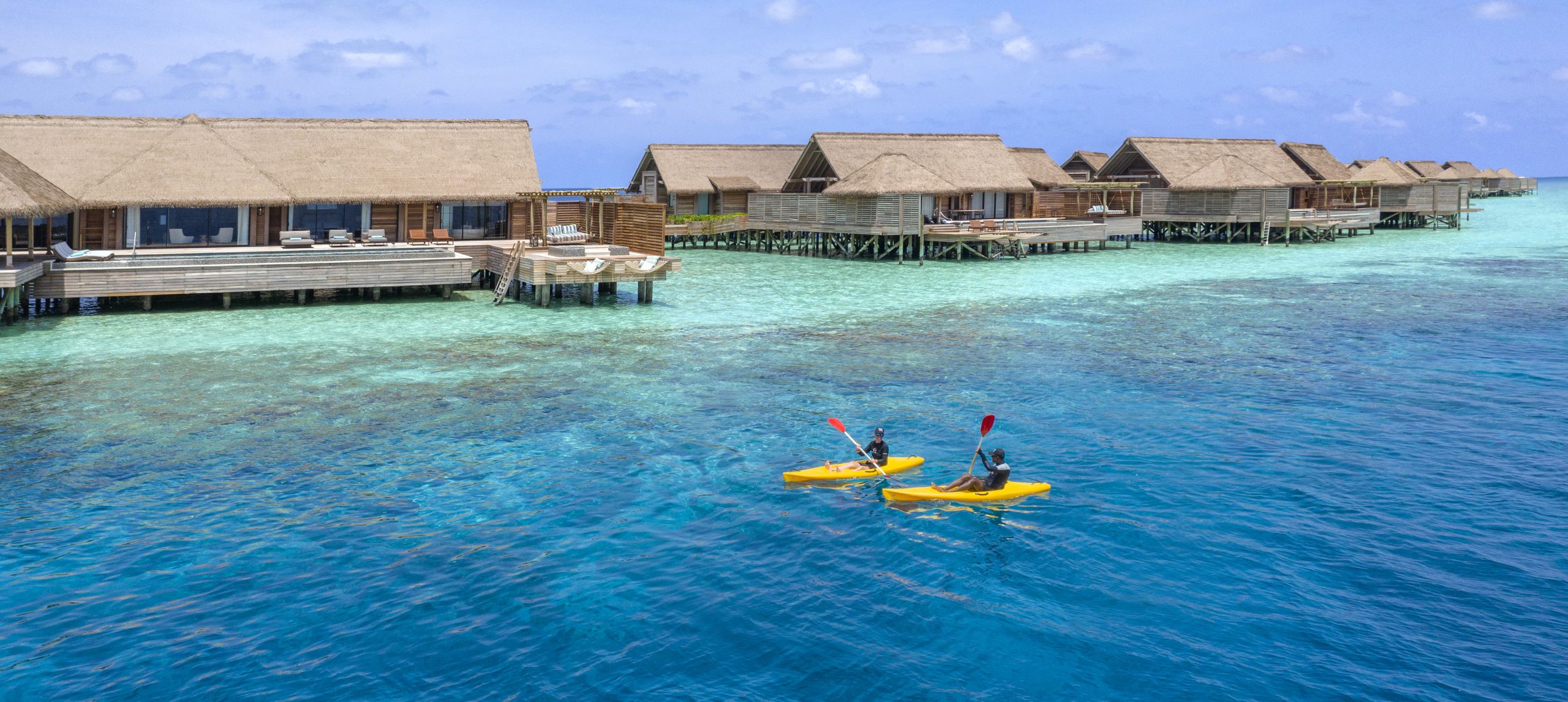 Two kayaks in lagoon with villas in the background