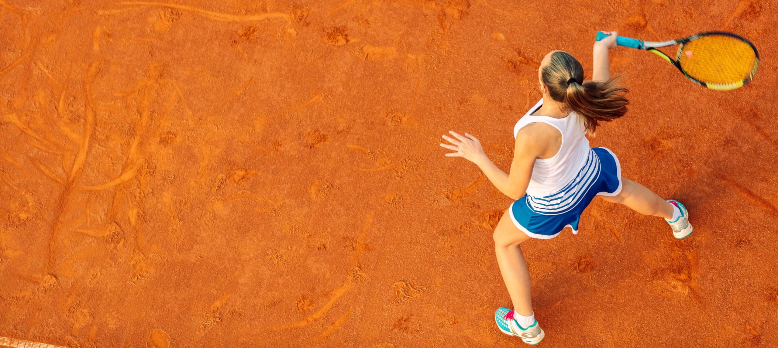 Kırmızı kortta tenis oynayan kız