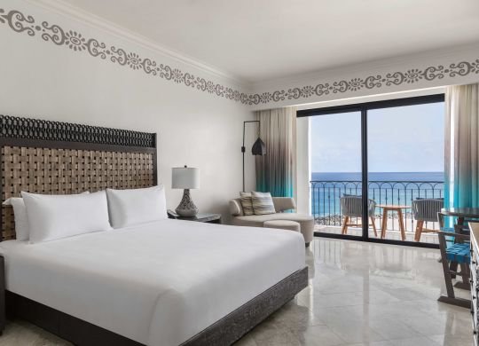 Chambre face à l'océan avec très grand lit, chaises et vue sur le balcon