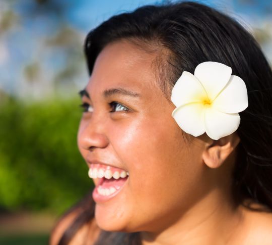 Woman smiling with a flower behind her ear
