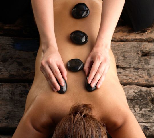 Therapist's Hands Placing Stone on Woman's Back