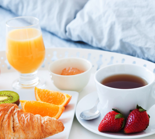 Close-up of Breakfast room service. Plate of fruit, coffee and orange juice.