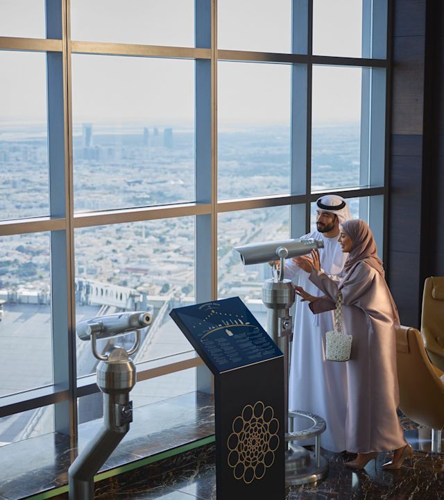 Man and woman on observation deck looking through telescope