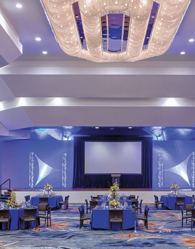 Ballroom setup with round tables and a projection screen