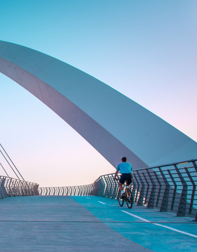 Man cycling over bridge at dawn