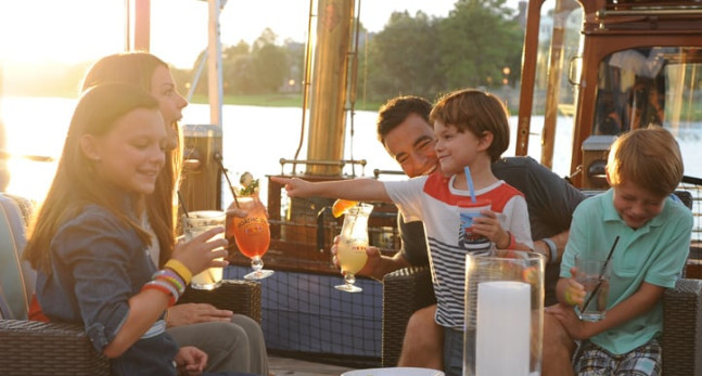 Family enjoying dinner and drinks by a lake