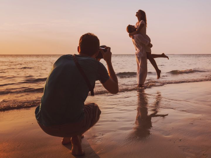 Photographer taking a picture of a couple on the beach