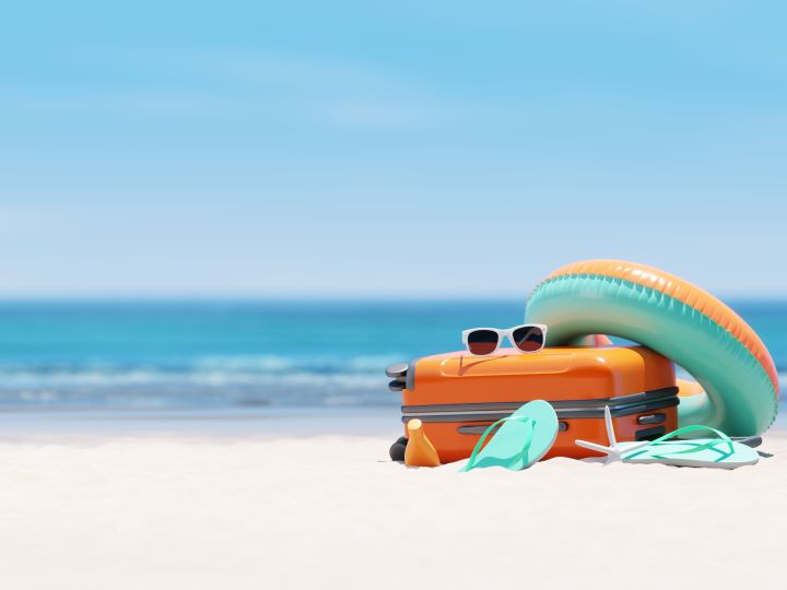 Suitcase and sunglasses on the beach