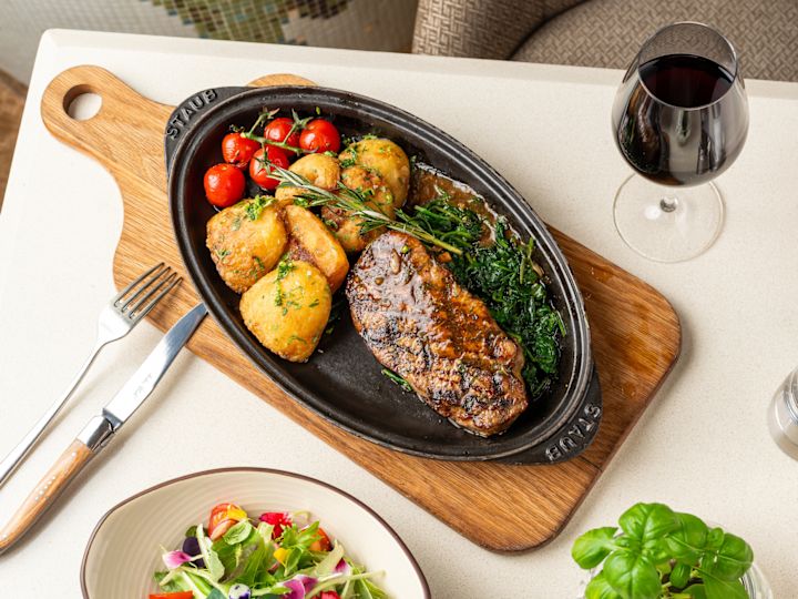 Steak, Potatoes and Salad on a Table with a Glass of Red Wine at Nahaam Restaurant