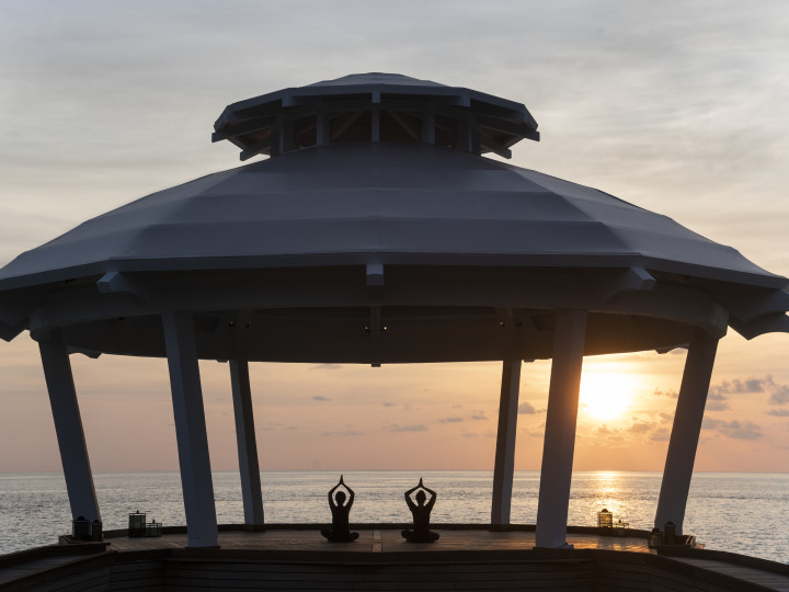 Two people in the Ocean Pavilion at sunset doing yoga
