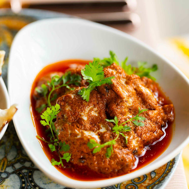 Lekko tostowany chleb Naan w koszu obok przyprawionego dania curry
