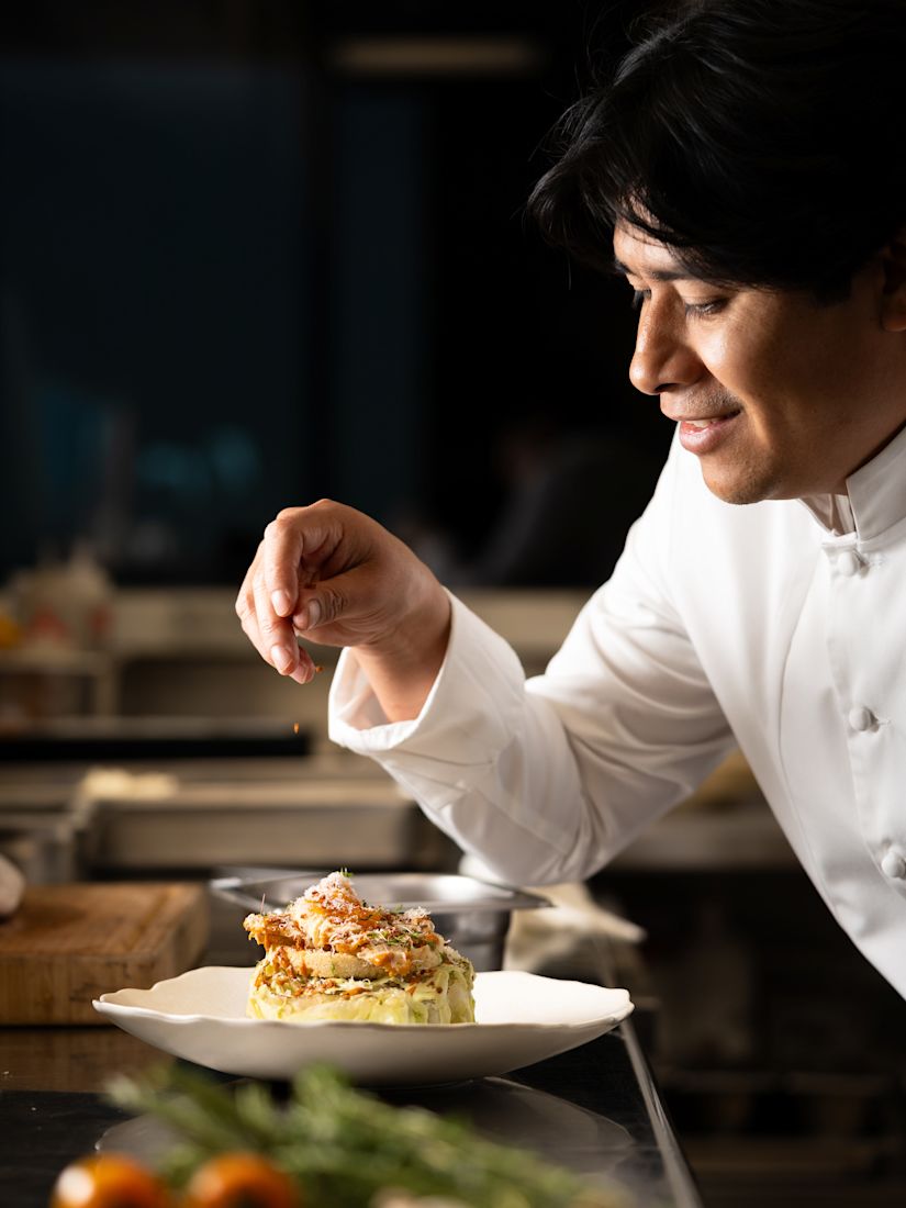 A chef seasoning food in Ray's Grill