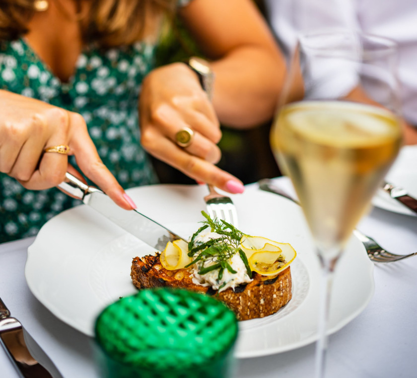 View of a lady's hands cutting into a brunch dish with champage.