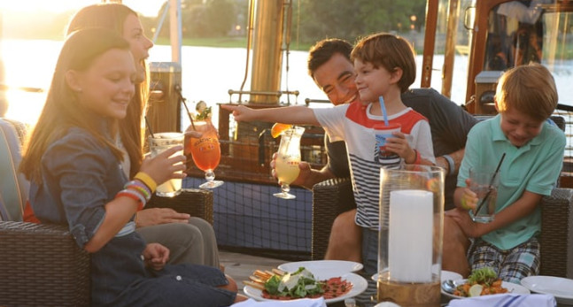 Family enjoying dinner and drinks by a lake