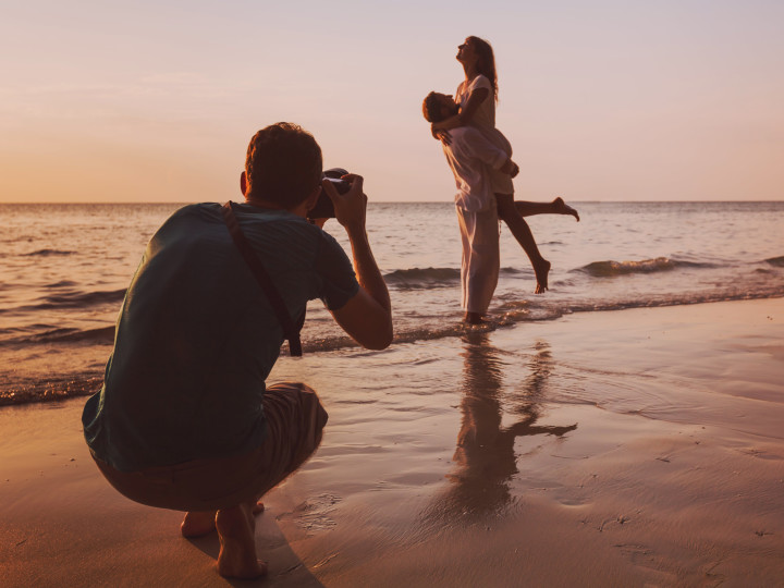 Photographer taking a picture of a couple on the beach